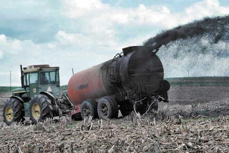 Macchina che spande fanghi sopra un terreno agricolo