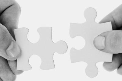 Due mani sostengono due pezzi di un puzzle che vanno ad incastrarsi.