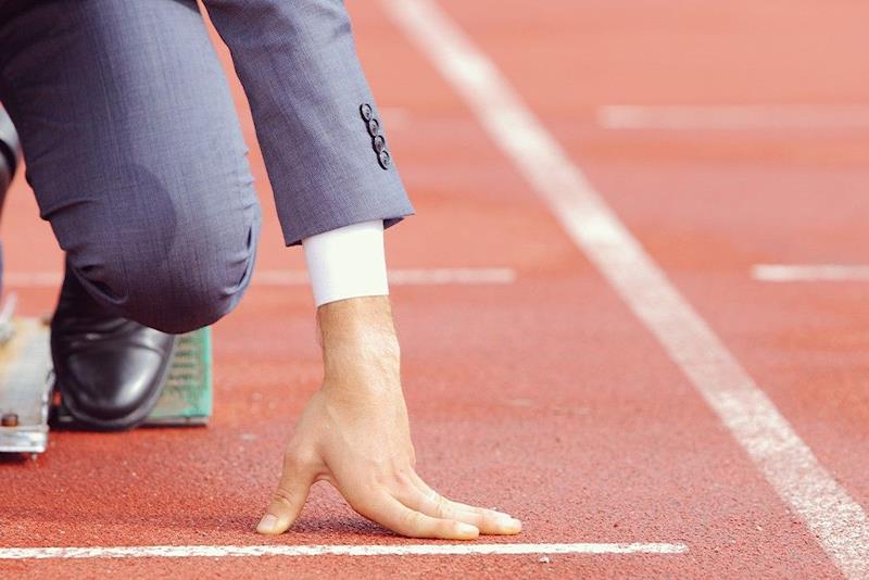 Persona sulla linea di partenza di una pista di atletica, a simboleggiare idealmente la ripresa.
