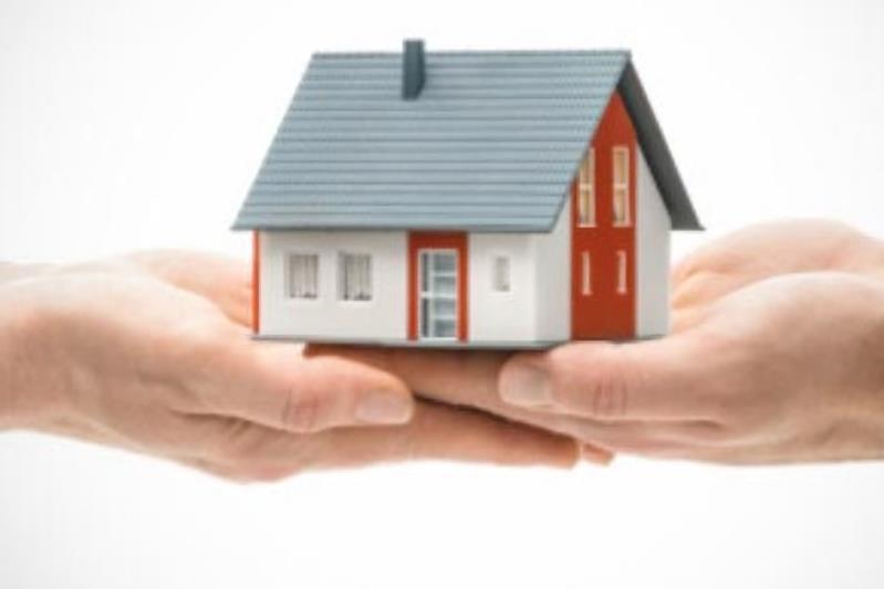 Due mani sostengono il modellino di una casa.